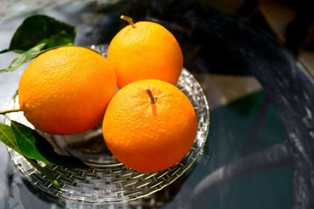 Plate with fresh ripe oranges on glass table, above view. Space for text