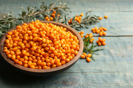 Ripe sea buckthorn berries on blue wooden tableの写真素材