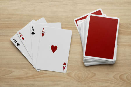Four aces and deck of playing cards on wooden table, flat layの写真素材