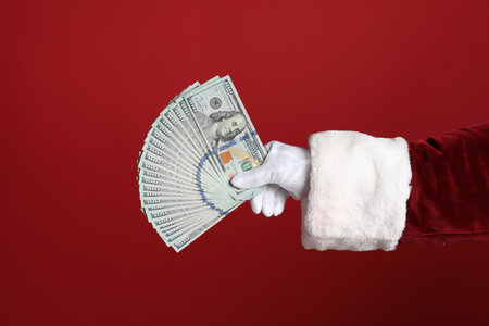 Santa holding dollar bills on red background, closeupの写真素材