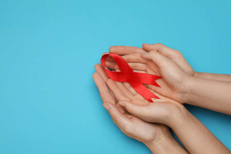 Woman and girl holding red ribbon on blue background, top view with space for text. AIDS disease awarenessの写真素材