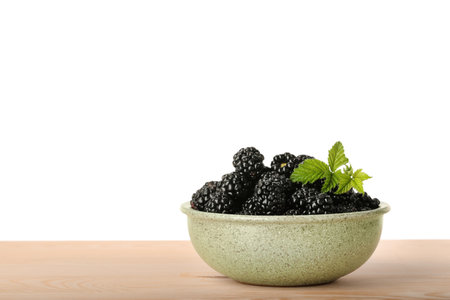 Bowl with fresh ripe blackberries on wooden table against white background, space for textの写真素材
