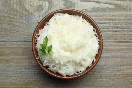 Tasty fermented cabbage with parsley on wooden table, top viewの写真素材