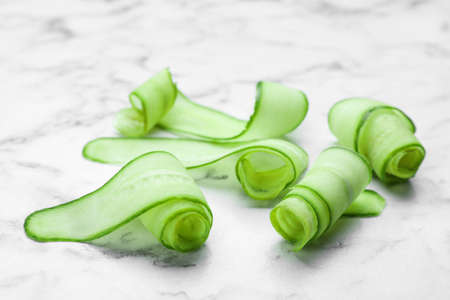 Slices of fresh ripe cucumber on white marble tableの写真素材