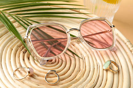Stylish sunglasses and rings on wicker mat, closeupの写真素材