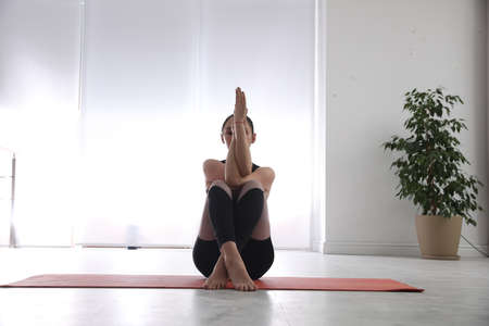 Woman practicing eagle asana in yoga studio. Garudasana posture
