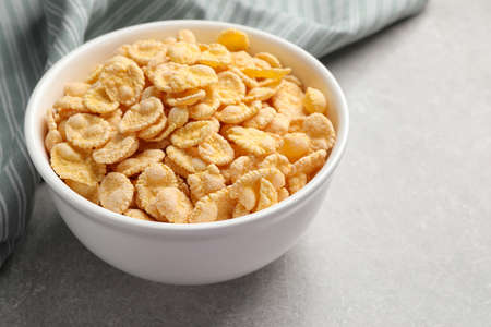 Bowl of tasty corn flakes on light gray background, closeup. Space for text