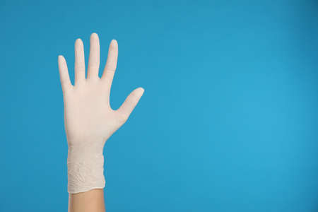 Doctor wearing medical gloves on light blue background, closeup. Space for textの写真素材