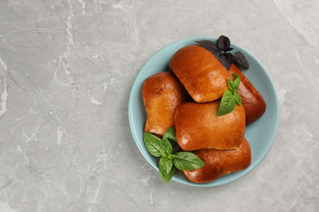 Delicious baked pirozhki and basil on light gray marble table, top view. Space for textの写真素材