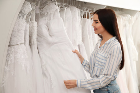 Young woman choosing wedding dress in salonの写真素材