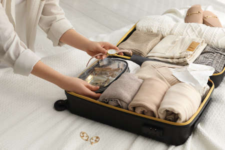 Woman packing suitcase for trip on bed, closeupの写真素材