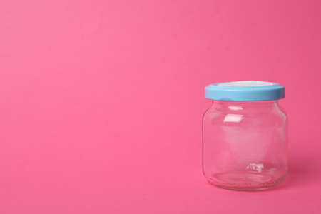 Closed empty glass jar on pink background, space for textの写真素材