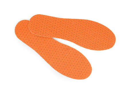 Pair of orange orthopedic insoles on white background, top view