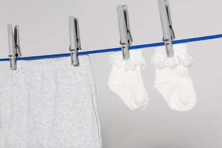 Different baby clothes drying on laundry line against light background, closeupの写真素材