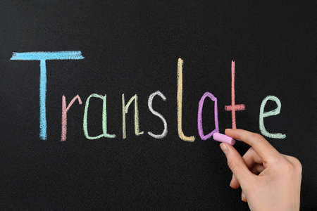 Woman writing word Translate with chalk on blackboard, closeupの写真素材