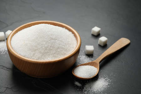 Granulated sugar in bowl on dark tableの写真素材