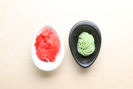 Bowls with swirl of wasabi paste and pickled ginger on white table, flat layの写真素材