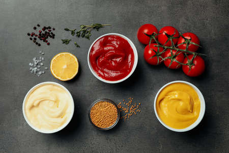Flat lay composition with ketchup, mustard, mayonnaise and ingredients on gray tableの写真素材