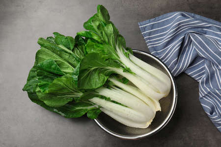 Fresh green pak choy cabbages with water drops in sieve on gray table, top viewの写真素材