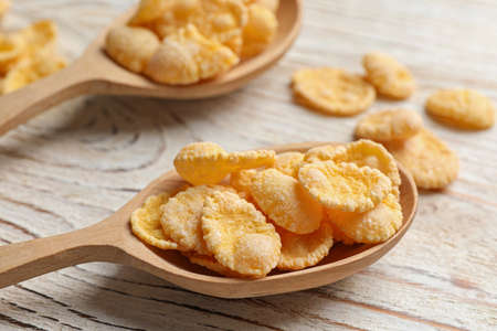 Two spoons and tasty corn flakes on white wooden table, closeup