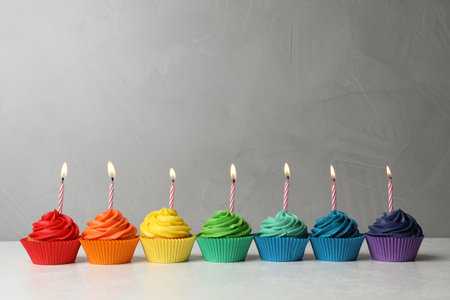 Delicious birthday cupcakes with burning candles on tableの写真素材