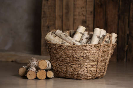 Wicker basket with cut firewood on floor indoorsの写真素材