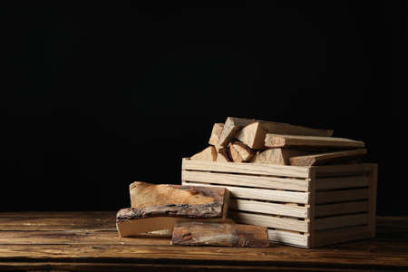 Cut firewood on table against black backgroundの写真素材