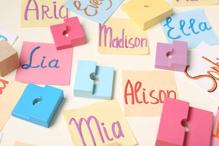 Colorful paper sheets with written different baby names and toys on beige backgroundの写真素材
