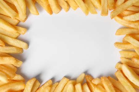 Frame of delicious french fries on white background, flat lay. Space for textの写真素材