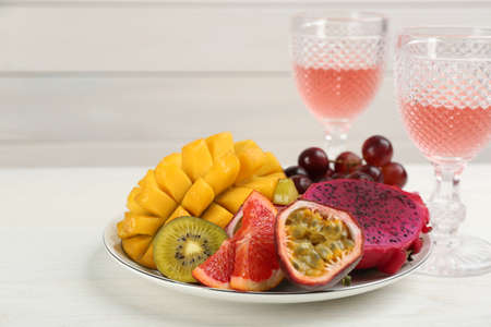 Delicious exotic fruits and wine on white wooden tableの写真素材