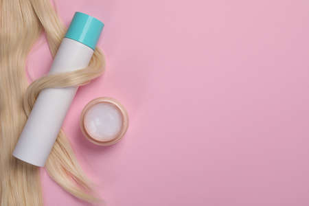 Lock of healthy blond hair and cosmetic products on pink background, flat lay. Space for textの写真素材