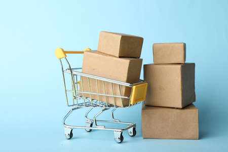 Shopping cart and boxes on light blue background. Logistics and wholesale conceptの写真素材