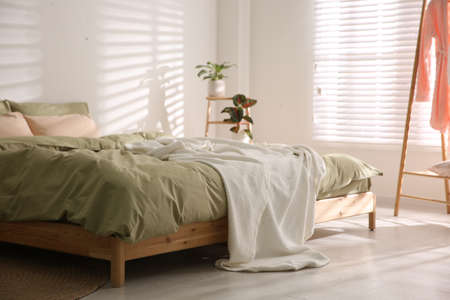Large bed with soft blanket in stylish room interior