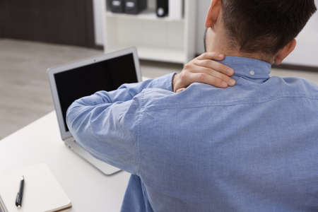 Man suffering from neck pain in office, back viewの写真素材