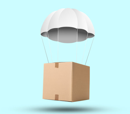 Cardboard box with parachute flying on light blue backgroundの写真素材