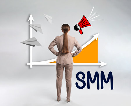 social media marketing. Young woman in business attire, abbreviation SMM and chart on light gray backgroundの写真素材