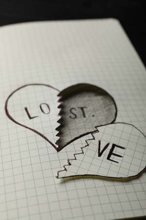 Broken heart with words LOVE and LOST in notebook on table, closeup. Relationship problems conceptの写真素材