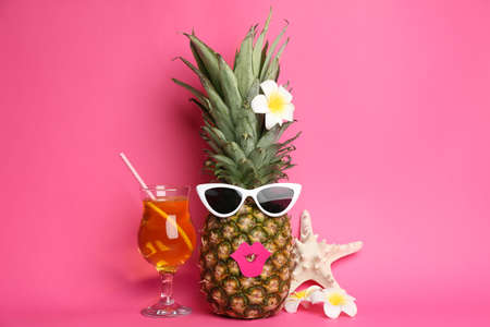 Funny pineapple with cocktail, plumeria flowers and starfish on pink background. creative conceptの写真素材