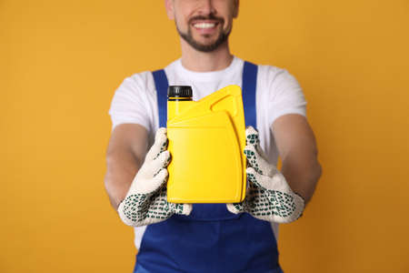 Man showing yellow container of motor oil on orange background, closeupの写真素材