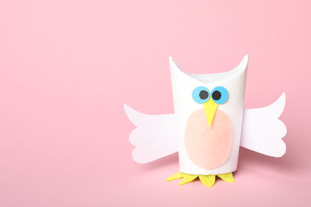 Toy owl made of toilet paper hub on pink background. Space for textの写真素材