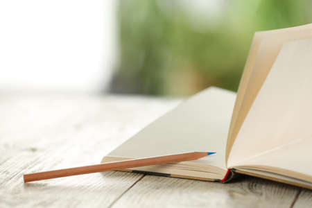 Closeup view of open notebook with pencil on white wooden table against blurred backgroundの写真素材
