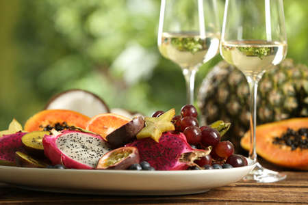 Delicious exotic fruits and wine on wooden tableの写真素材