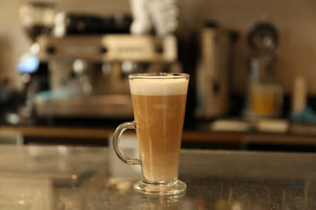 Glass with delicious coffee on countertop in cafe indoors