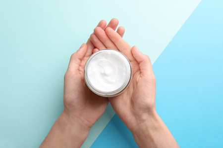 Woman holding jar of hand cream on color background, top viewの写真素材