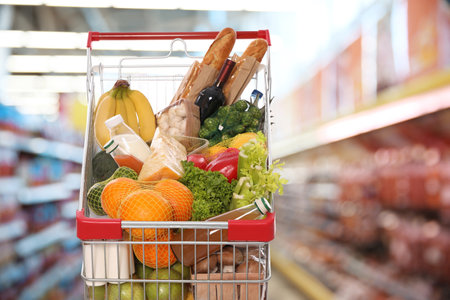 Shopping cart with different groceries in supermarketの写真素材