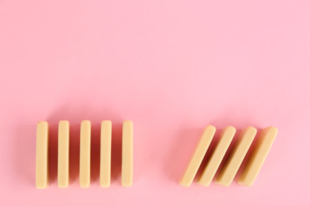 White domino tiles on pink background, flat lay. Space for text