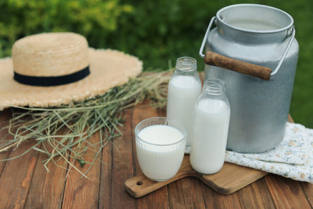 Fresh milk on wooden table outdoors. Space for text