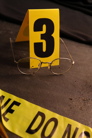 Crime scene marker and glasses on black slate tableの写真素材