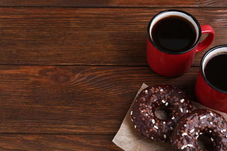 Two frosted donuts with sprinkles and cups of coffee on wooden table, space for textの写真素材