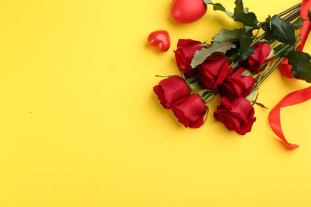 Beautiful red roses and decorative hearts on yellow background, flat lay with space for text. Valentine's Day celebrationの写真素材